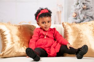 Holiday photo session with decorated tree and gold throw pillows on white sofa.