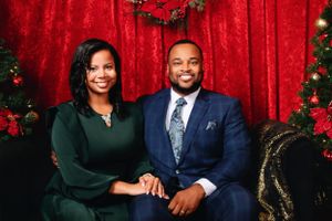 Professional holiday portraits with family members in formal attire against red backdrop.