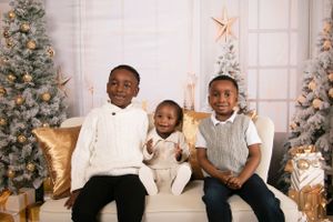 Winter family photoshoot with decorated Christmas trees and gold star decorations.