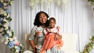Mother and child photo session with floral backdrop and white curtains.