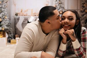 A couple shares an intimate moment in front of a decorated Christmas tree and holiday decor.