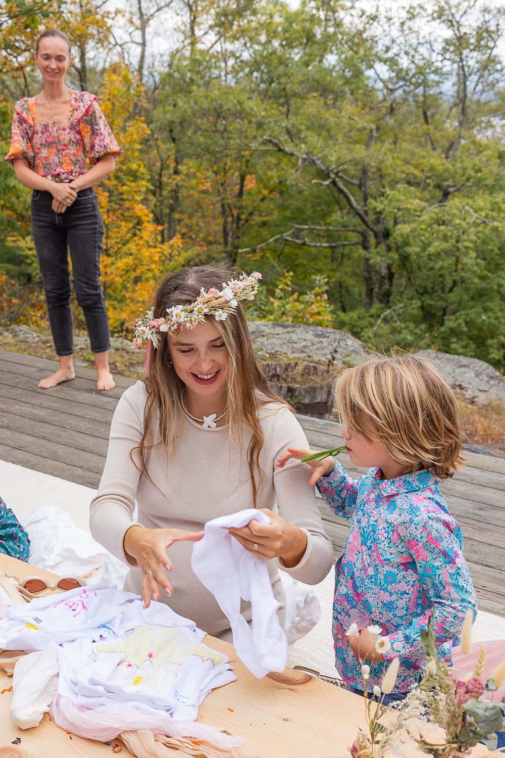 People decorating baby clothes during outdoor celebration with autumn foliage in background.