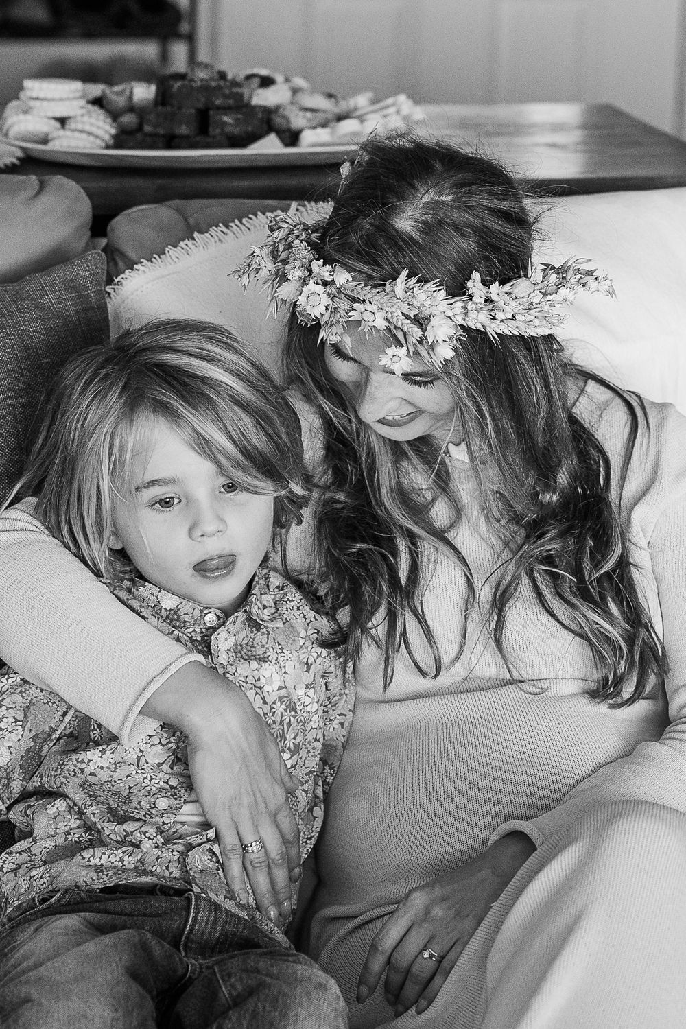 Black and white intimate portrait of people relaxing on couch with floral crown.