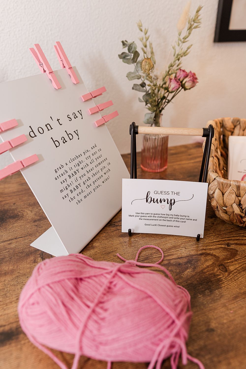 Baby shower decoration with pink clothespins and yarn on wooden table.