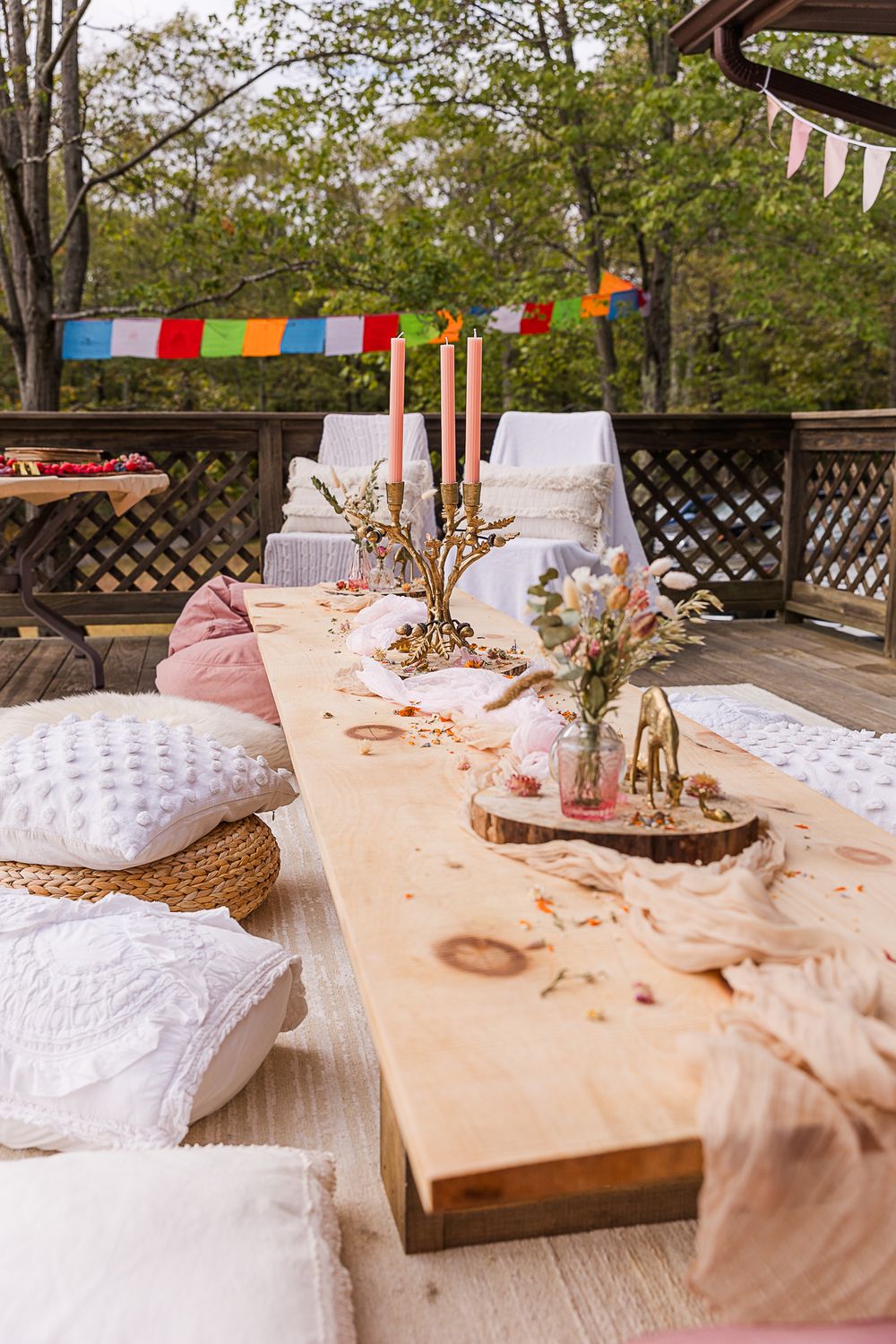 Outdoor baby shower table setting with colorful bunting and rustic decorations.
