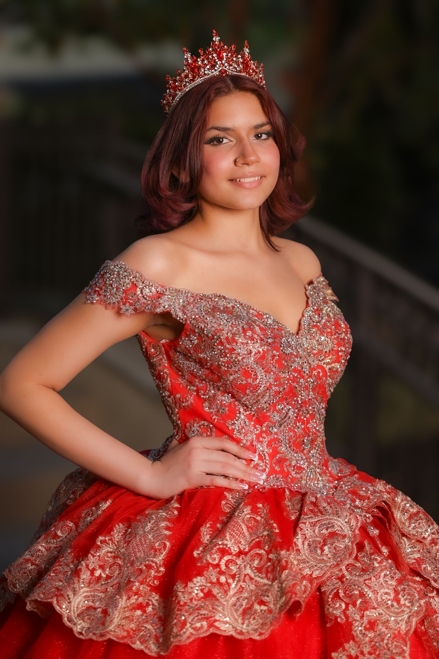 An elegant red and silver quinceañera ball gown with off-shoulder design and intricate lace details, paired with a sparkling tiara.