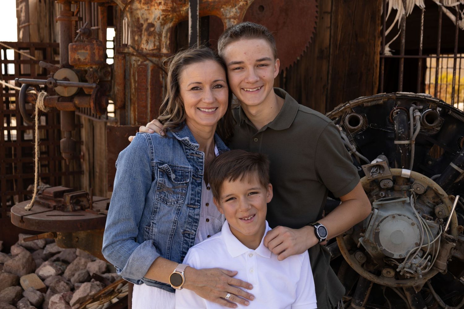 Family group poses together against rustic industrial machinery background.