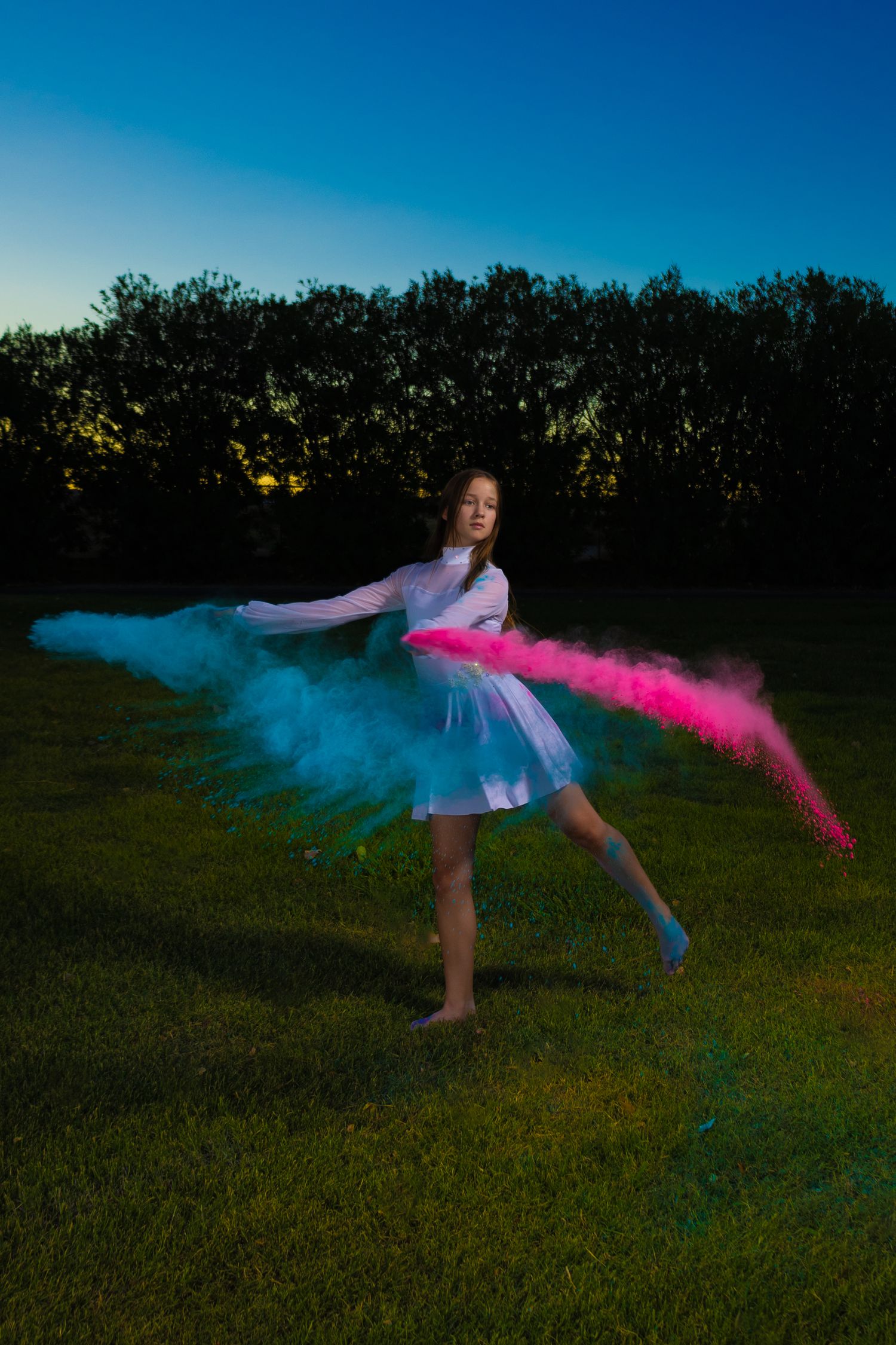 Dance performance with blue and pink powder effects at twilight.
