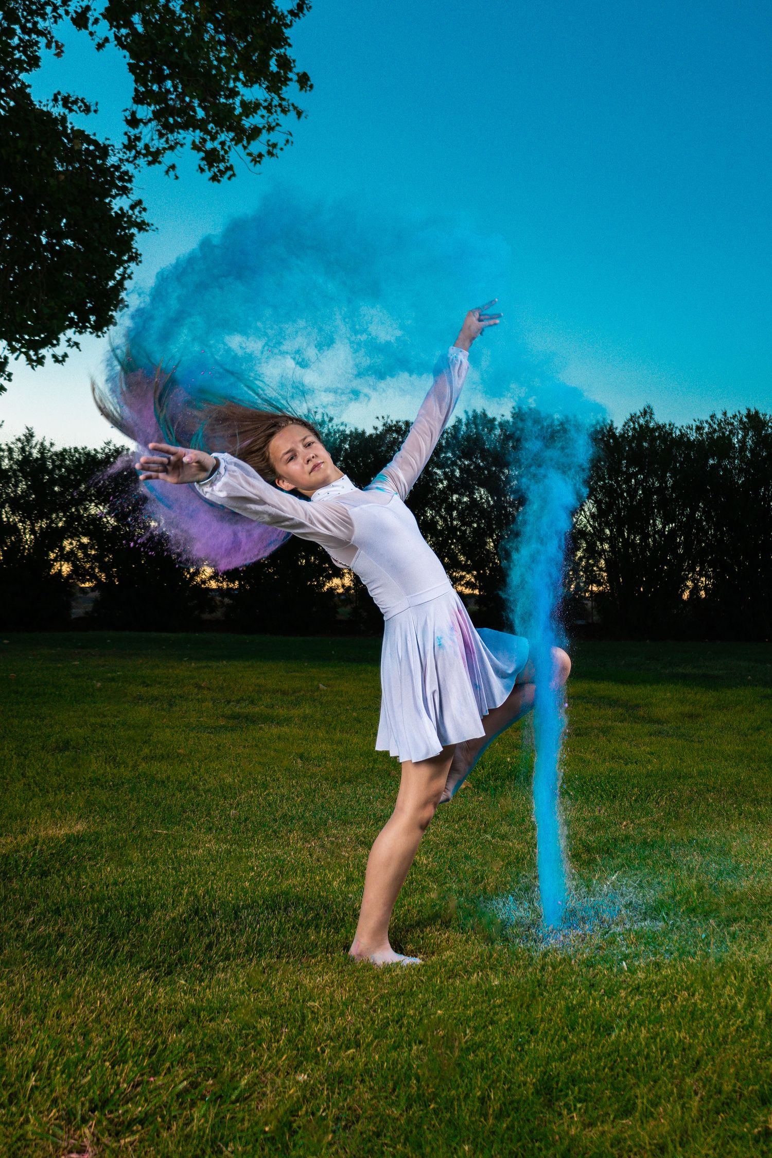 Dynamic dance movement captured with blue powder effects on grassy field.