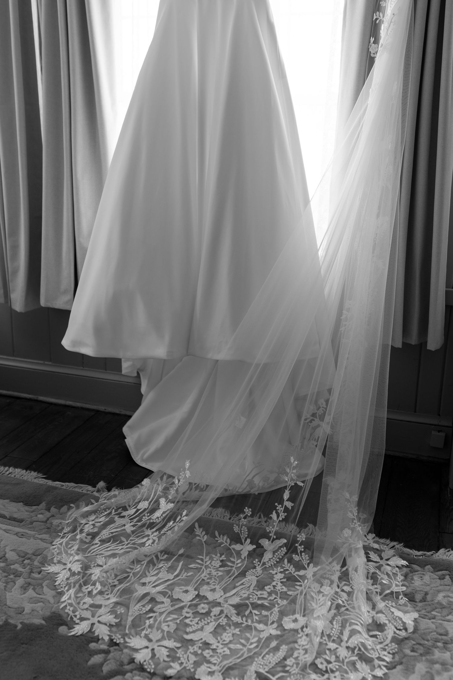 Black and white photo of newlyweds walking hand in hand through a rustic barn venue after their wedding ceremony.