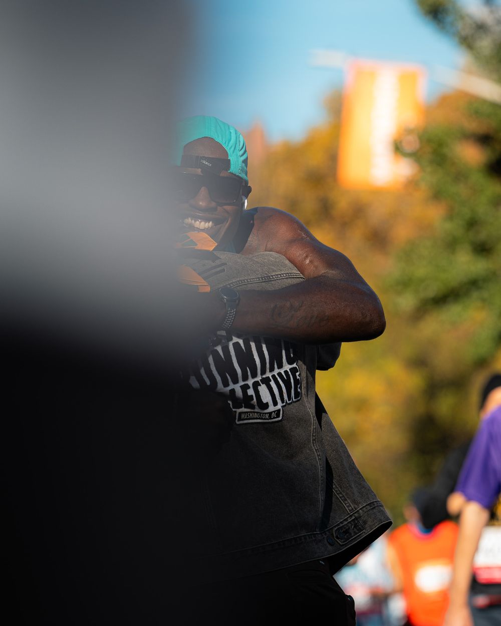 Runner in a black District Running Collective jean jacket smiling during marathon event.