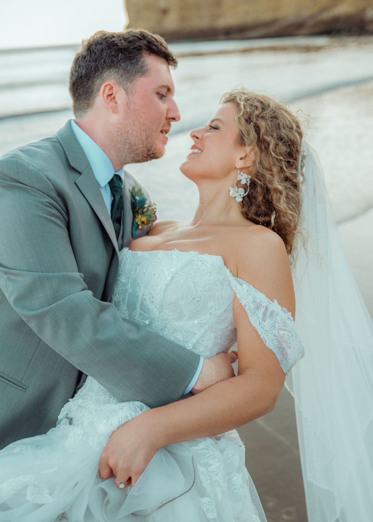 A couple in formal wedding attire poses on a forest path with evergreen trees creating a natural tunnel effect and cinematic photography.