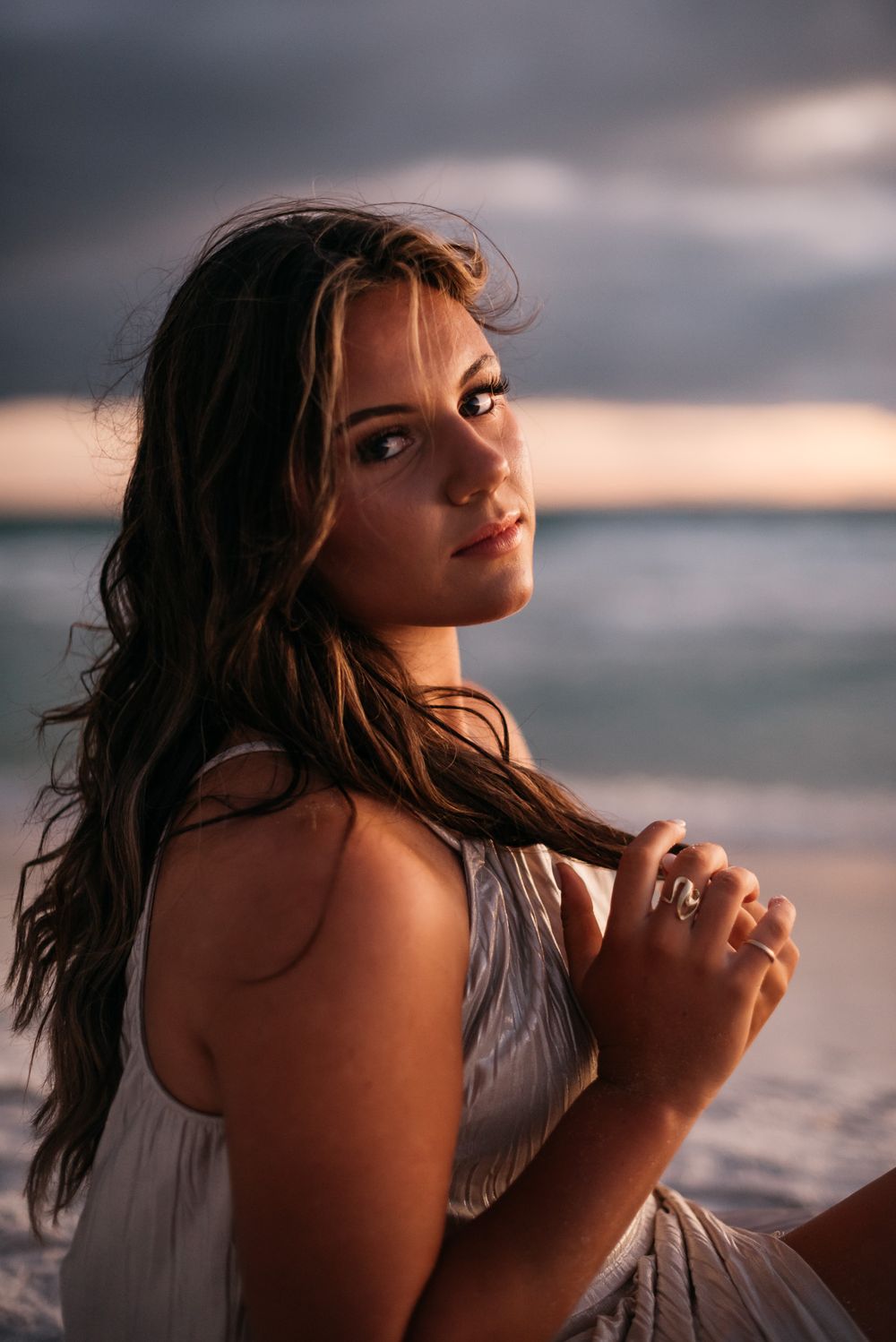 Portrait at sunset with ocean backdrop and warm golden lighting.