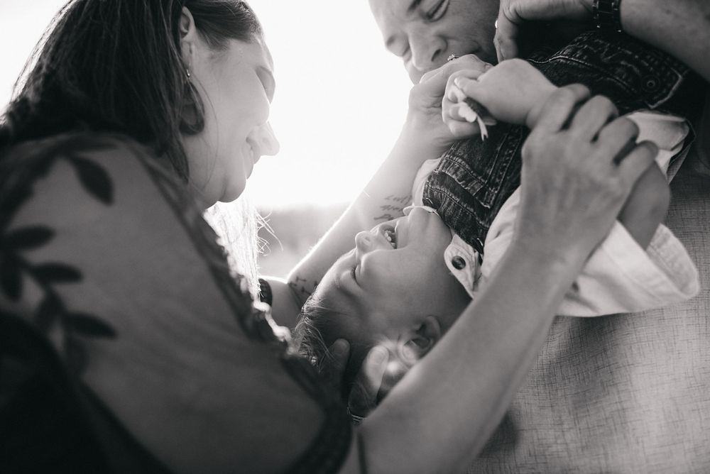 Black and white tender moment between family members with sunlight streaming through window in background.