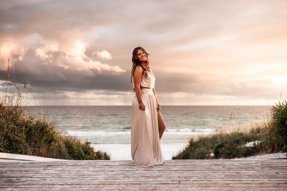 A flowing dress catches the sea breeze during a romantic beach photoshoot at sunset.