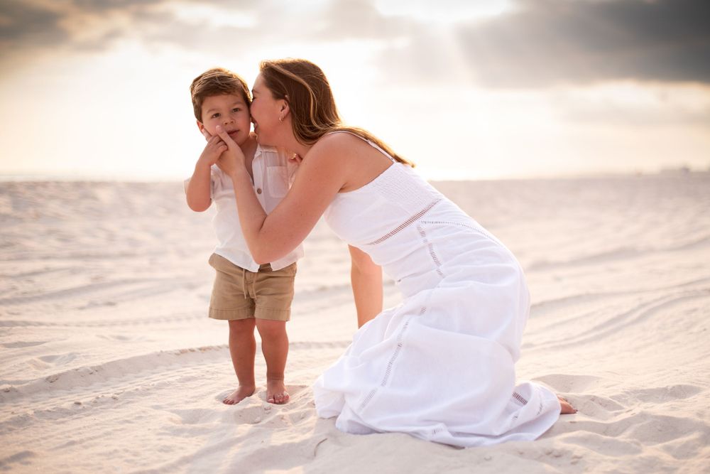 Tender family moments captured on white sandy beach during sunset.