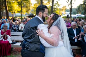 Wedding ceremony kiss captured outdoors with guests watching.