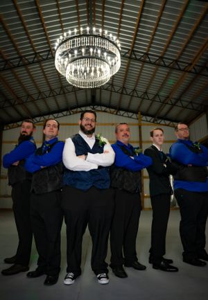 Groomsmen in matching blue and black attire pose dramatically under a crystal chandelier.