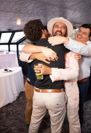 Wedding guests and couple share warm embraces during reception celebration.