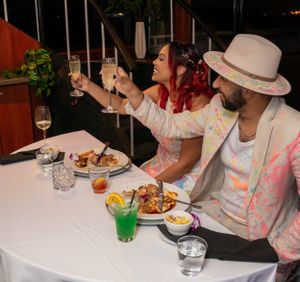 Wedding guests enjoying a meal together at reception tables decorated with white linens.