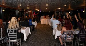 Large reception hall filled with guests seated at round tables for a wedding celebration.
