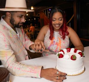 White wedding cake with red strawberry decorations being shared at a reception.