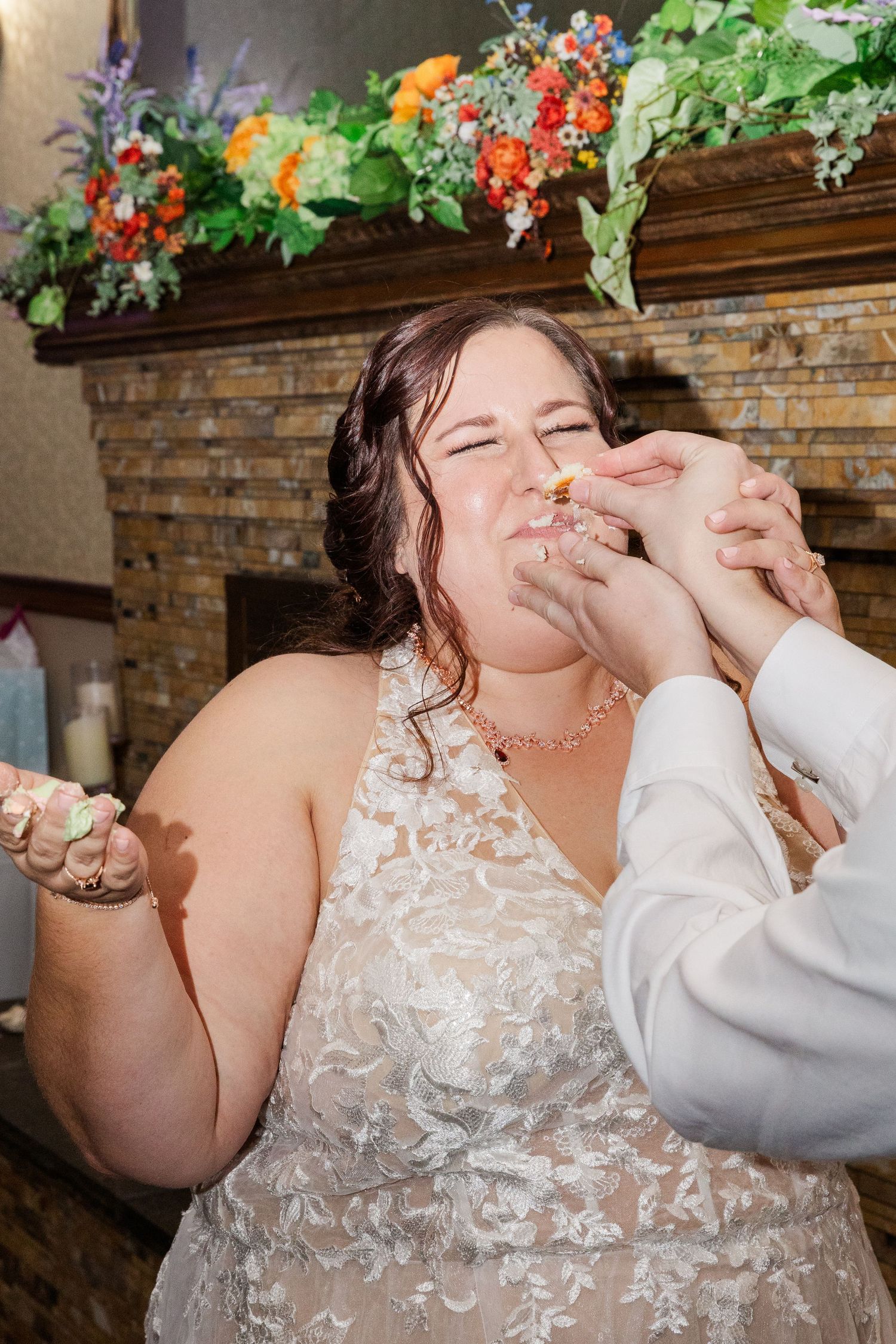 Bride enjoys cake during traditional wedding cake feeding moment.