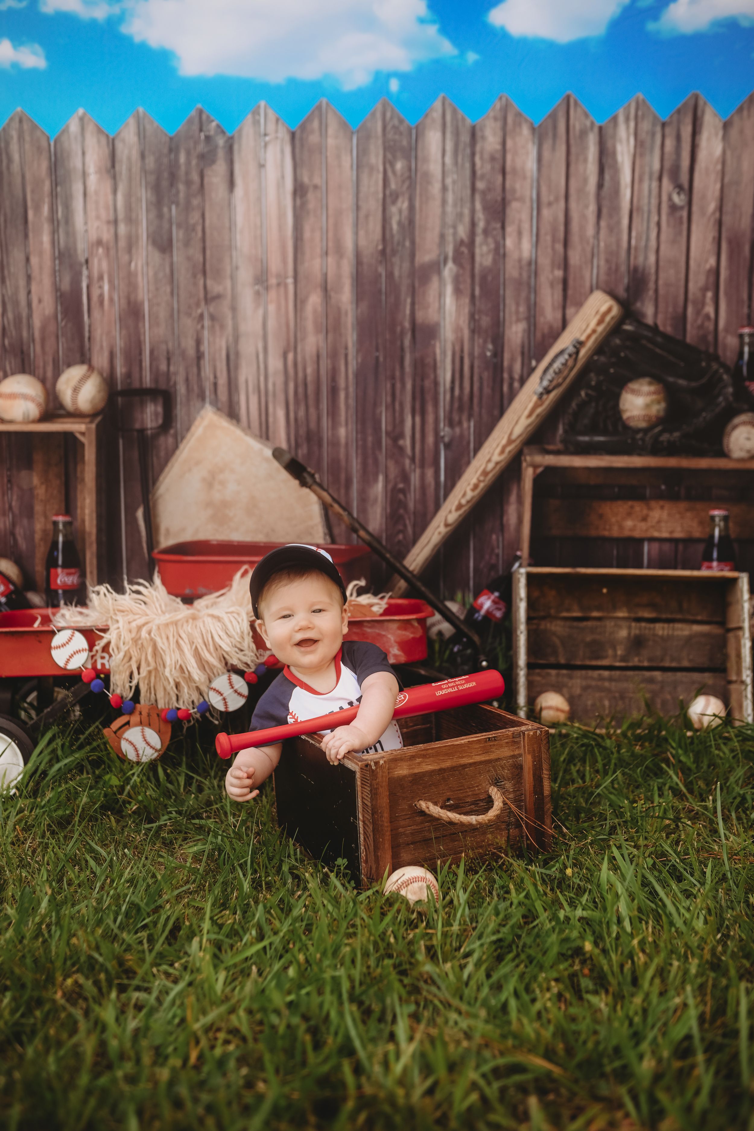 Baseball themed photo shoot with props and wooden fence in outdoor setting.