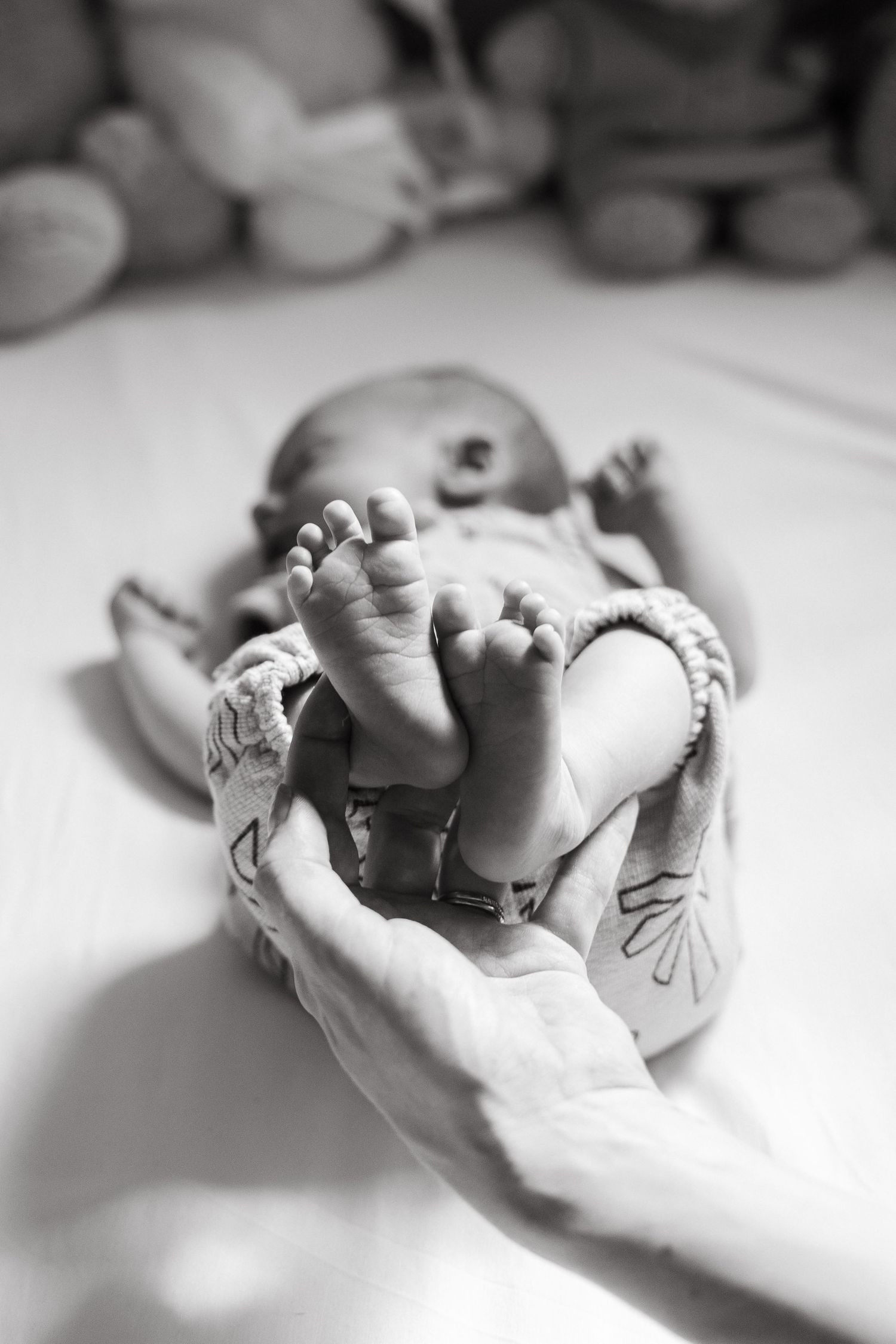 Close-up black and white photo of tiny baby feet being held.