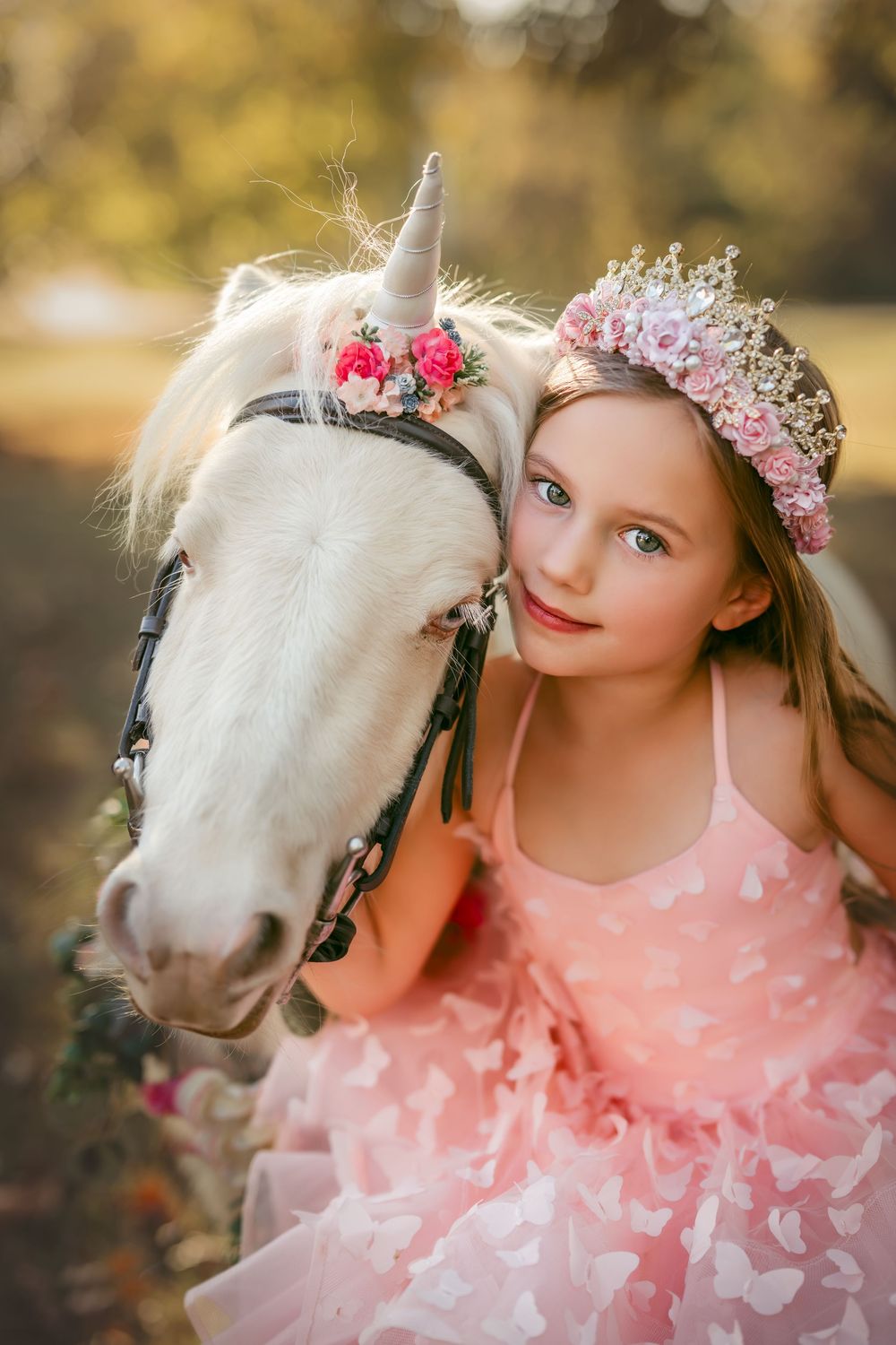 A magical portrait series featuring a white pony and a child in a pink dress adorned with butterflies and a floral crown.