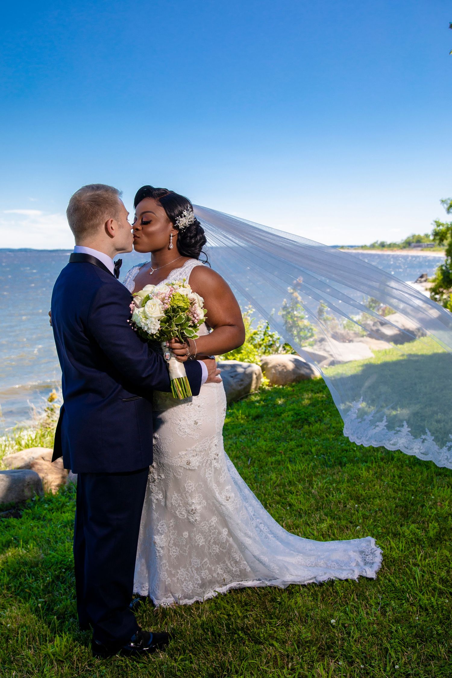 Beautiful beach wedding ceremony with flowing veil caught in the ocean breeze.