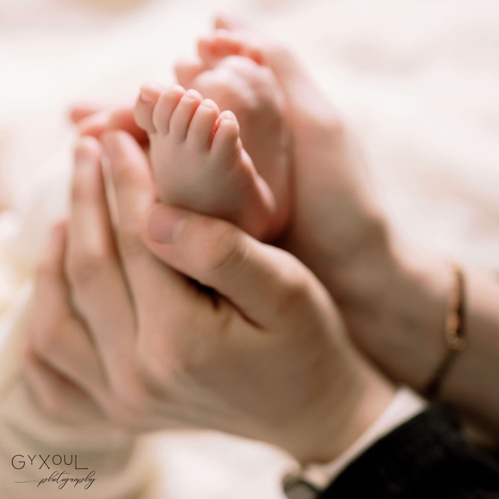 Close-up of tiny baby feet being gently held in adult hands.