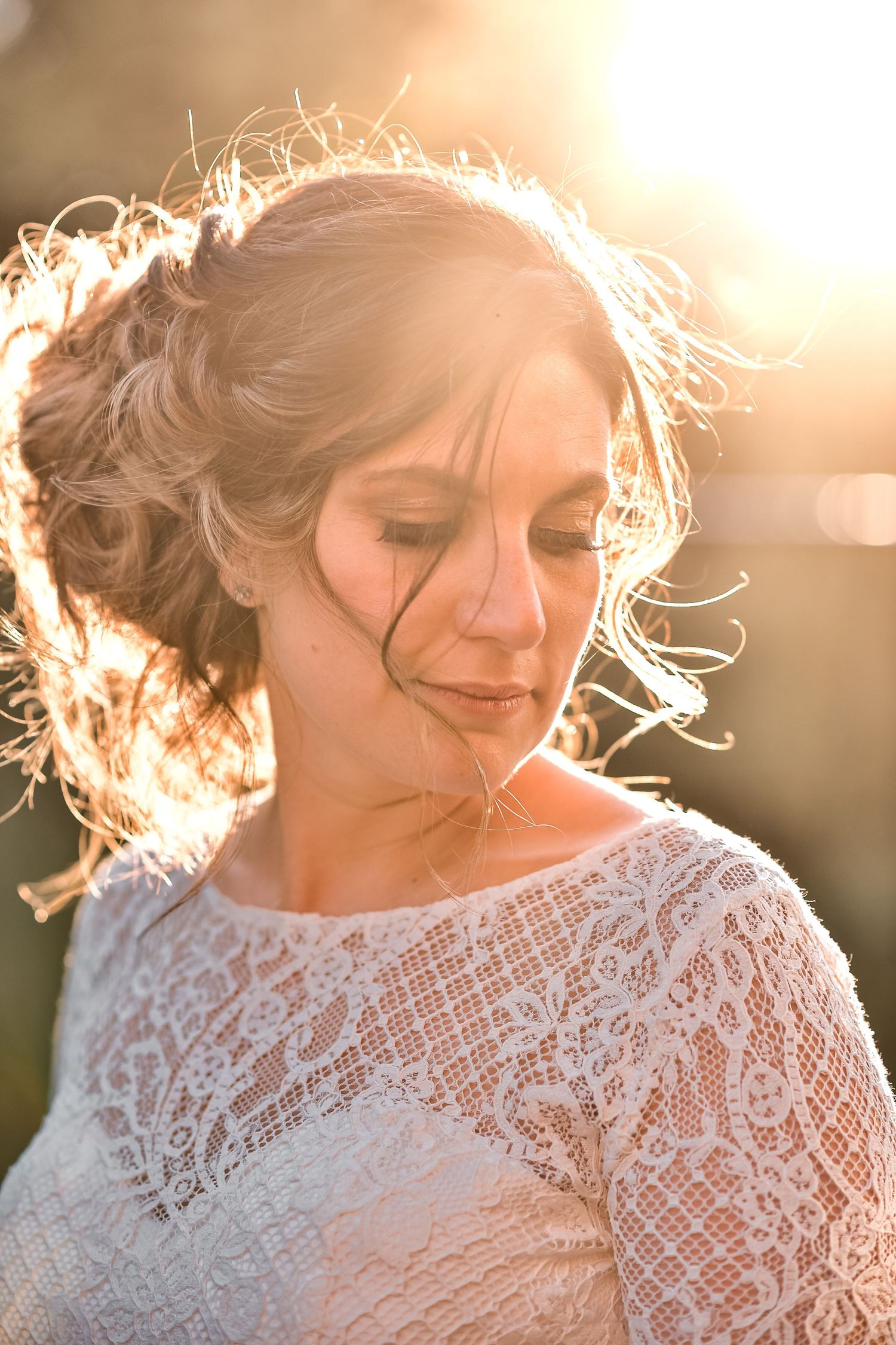 Ethereal bridal portrait with backlit lace dress and soft glowing golden sunlight creating a dreamy halo effect.