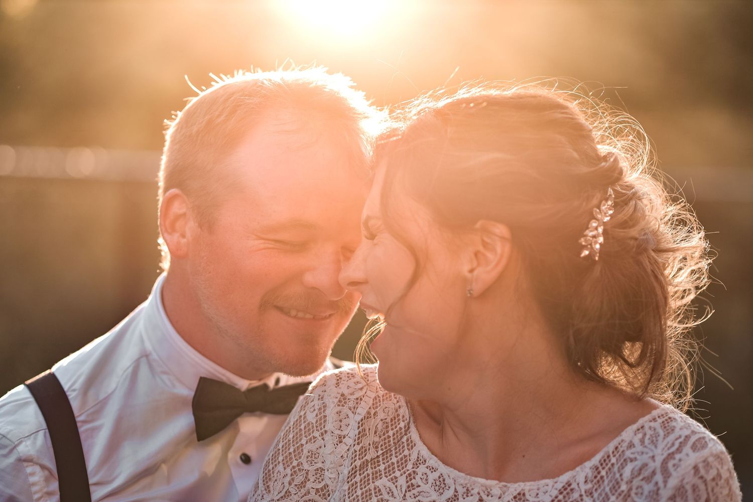 A romantic sunset moment between a couple in formal wedding attire with a glowing backlit effect.