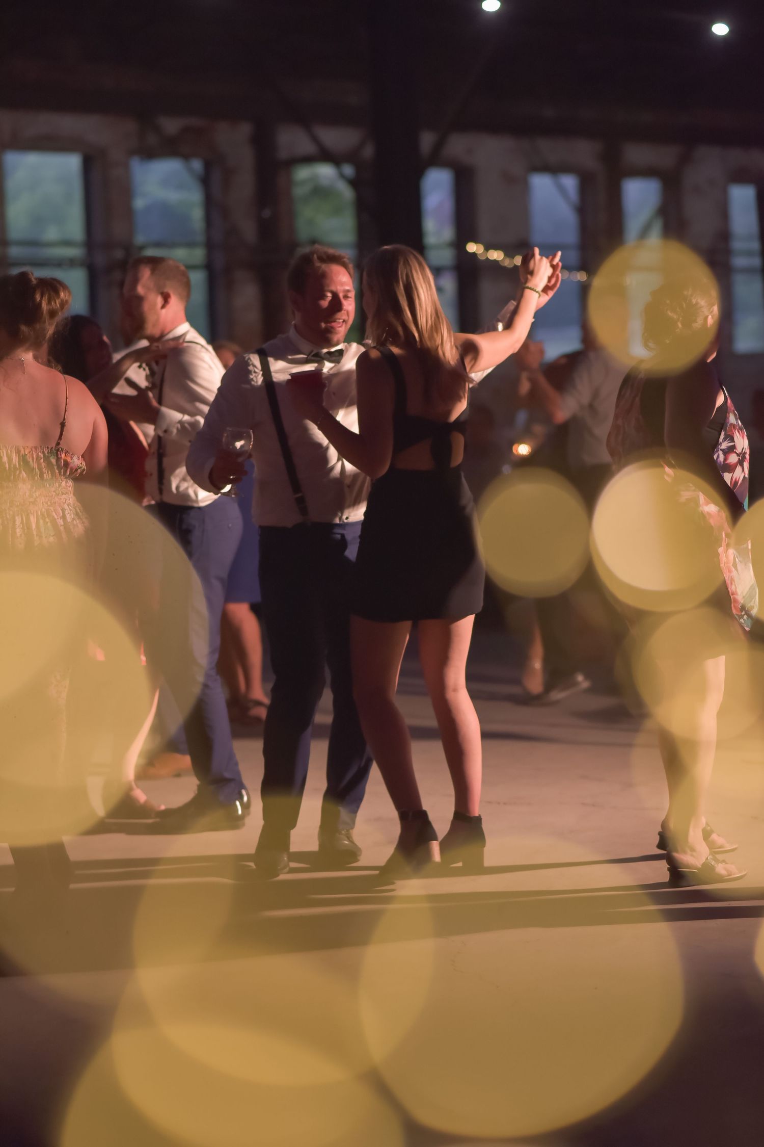 People dancing together at a party with glowing bokeh lights creating a dreamy atmosphere on the dance floor.