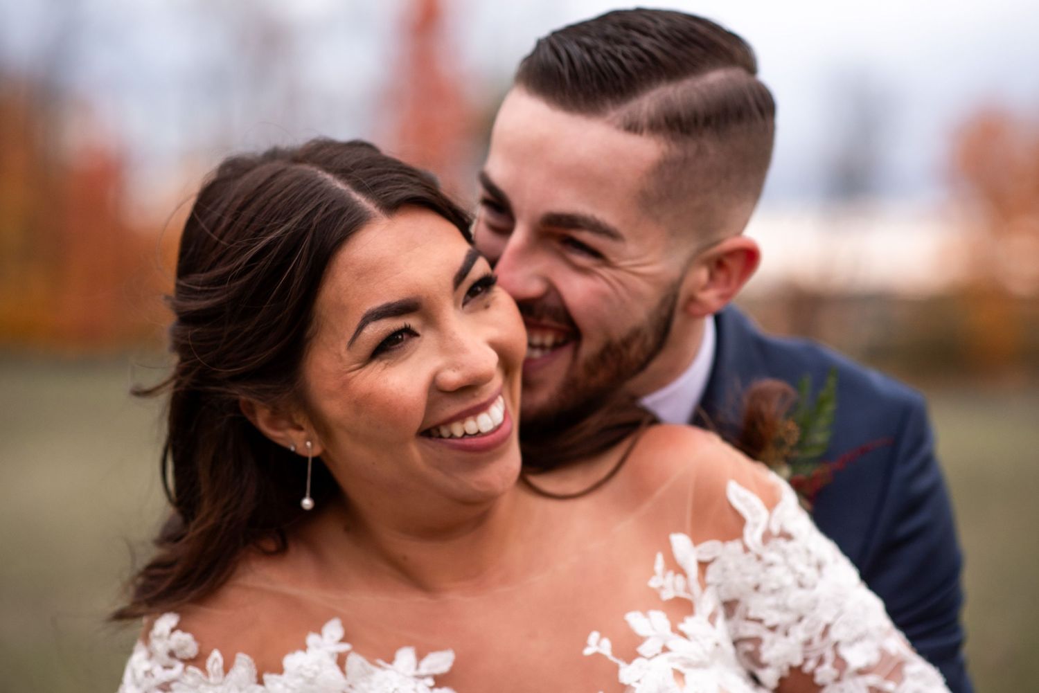 A joyful romantic moment shared between a couple on their wedding day in an autumn setting.