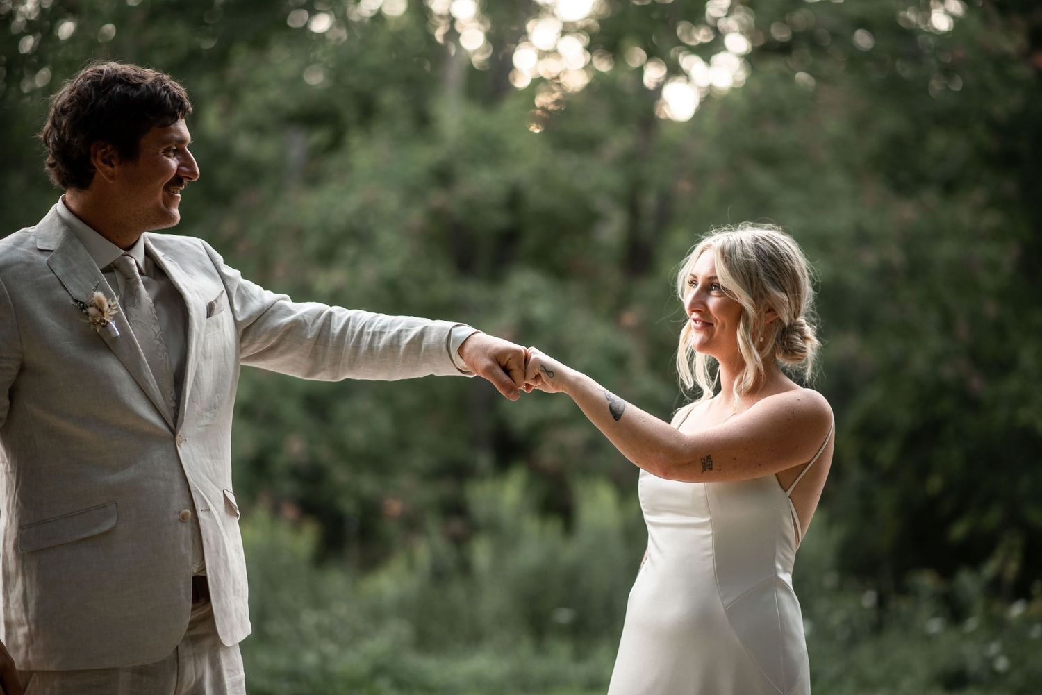 Newlyweds share a joyful moment together holding hands in an outdoor garden setting at sunset.