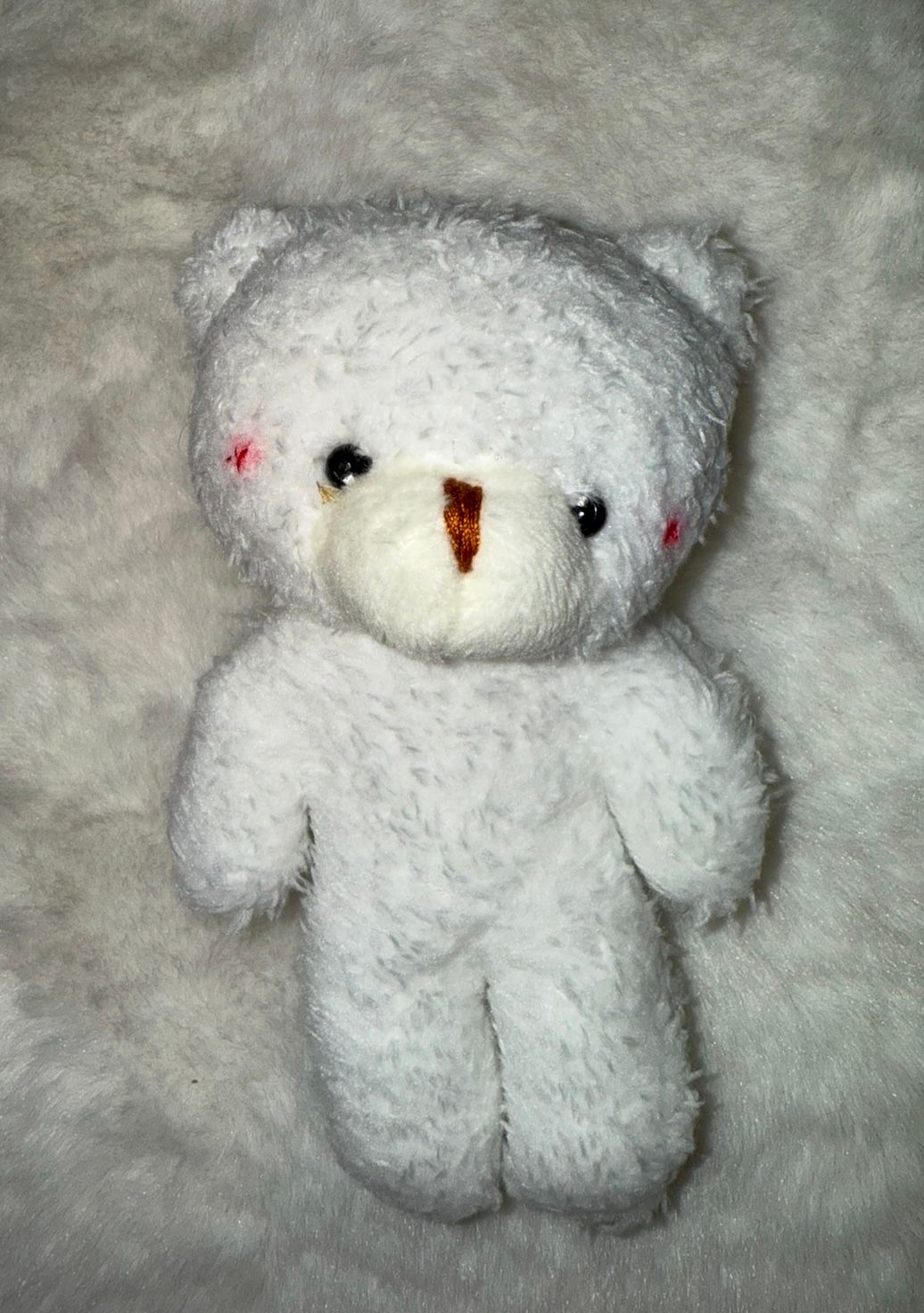 A fluffy white plush teddy bear with red accents photographed from different angles.