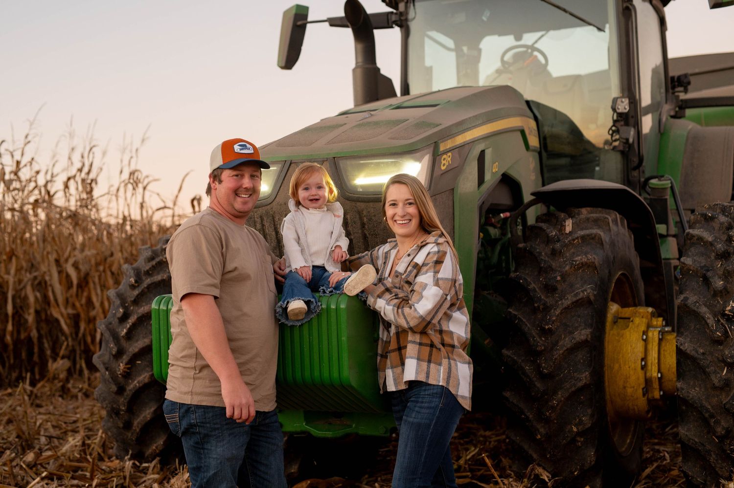 Family gathered in front of their farm tractor during harvest season.