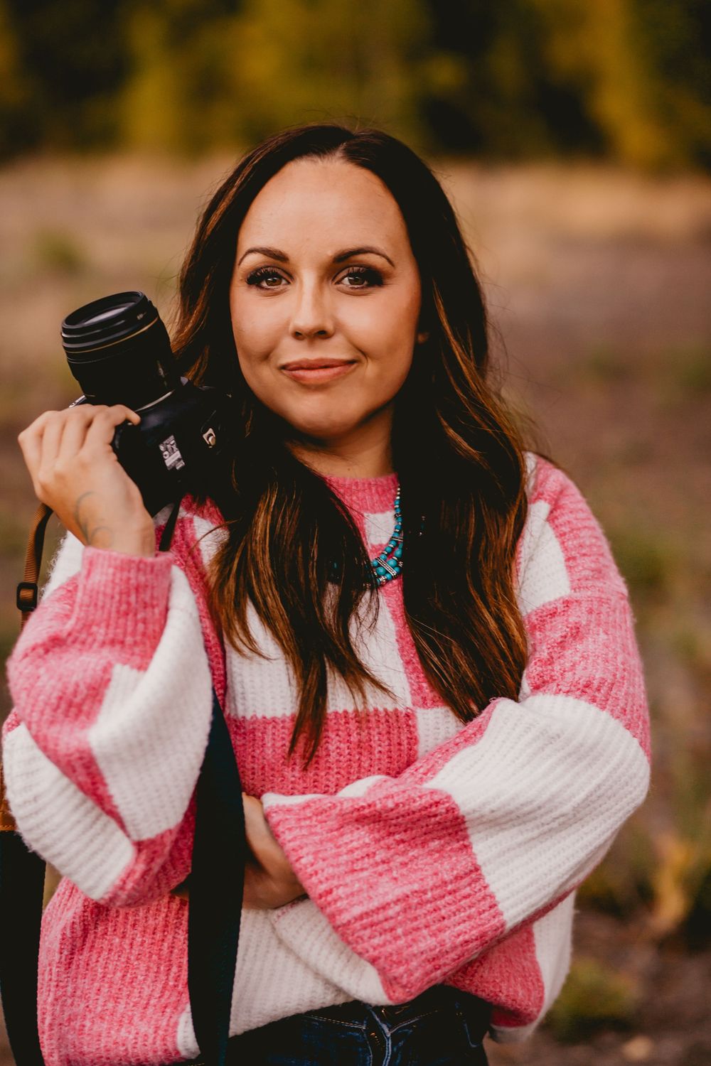 A series of photos showing someone wearing a cozy pink and white striped sweater against an autumn background.