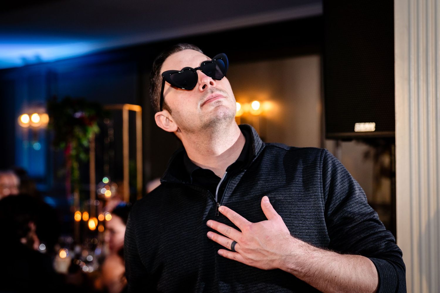 Person wearing sunglasses in a dimly lit venue with dramatic lighting effects.
