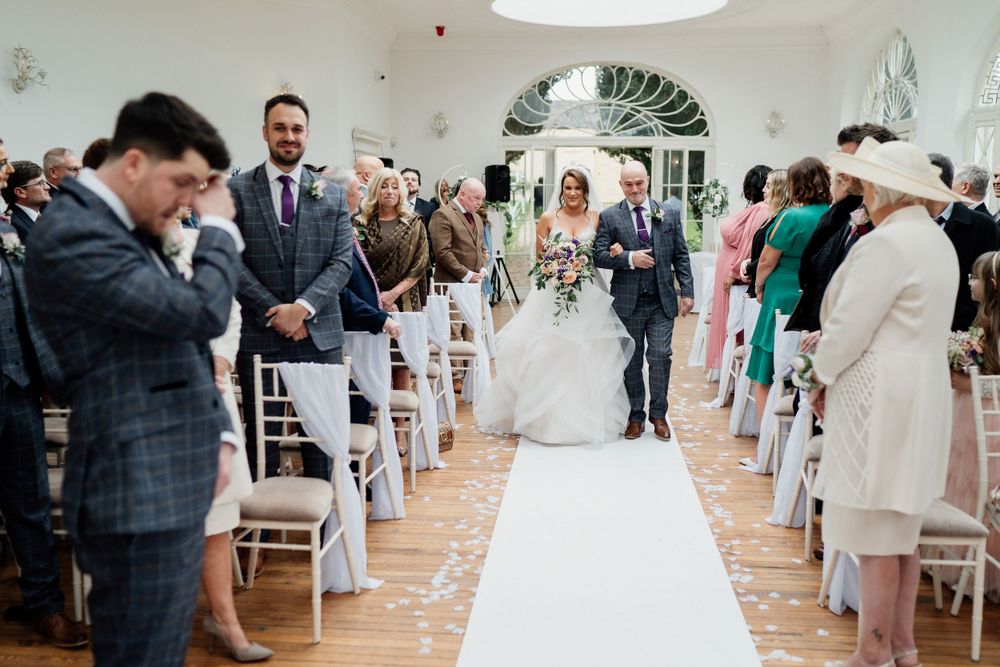 Wedding ceremony in progress with emotional reactions in bright indoor venue.