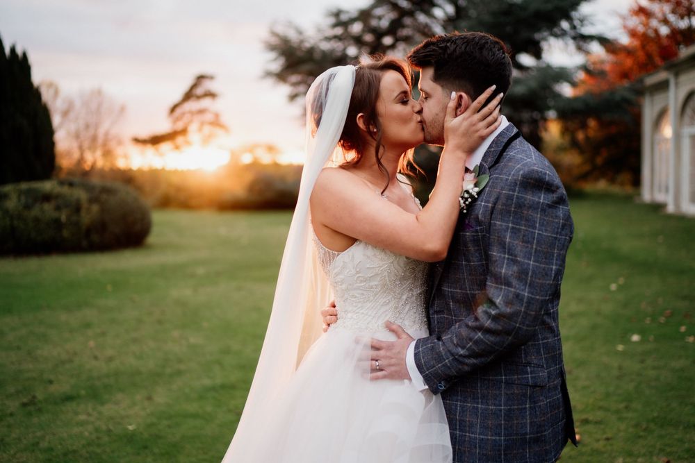 Intimate moment between couple in wedding attire during golden hour sunset.