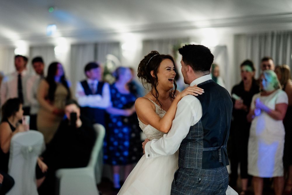 Couple shares a romantic dance moment during their wedding reception with blue lighting effects.