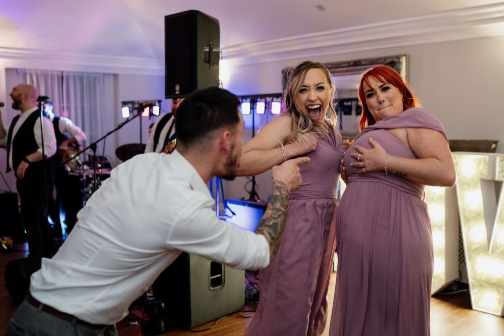 Wedding guests having fun and interacting near the dance floor with band equipment visible.