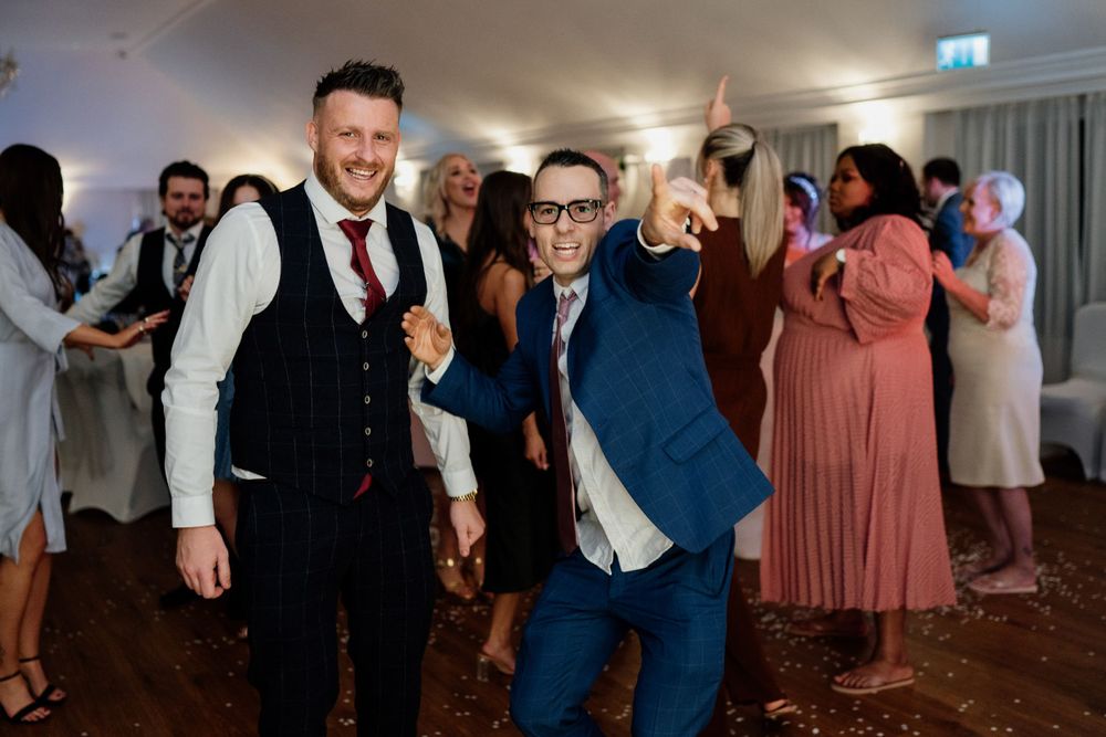 Guests enjoying themselves on the dance floor at a wedding reception in formal attire.