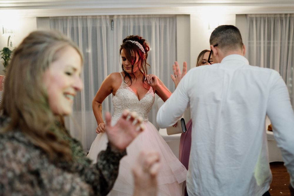 Wedding guests dancing and celebrating at a reception with white curtained walls.