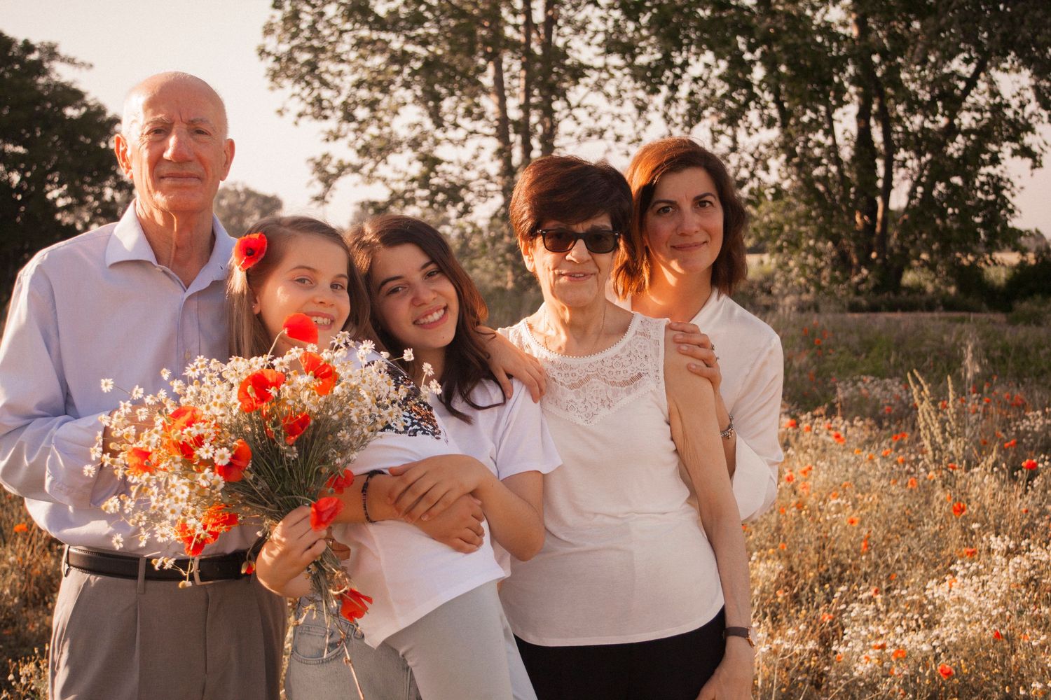 Famiglia con mamma, nonni, figlie, sorelle, nonna e nonno, nonni insieme alle nipoti. Campo di fiori, margherite, papaveri, fiori bianchi