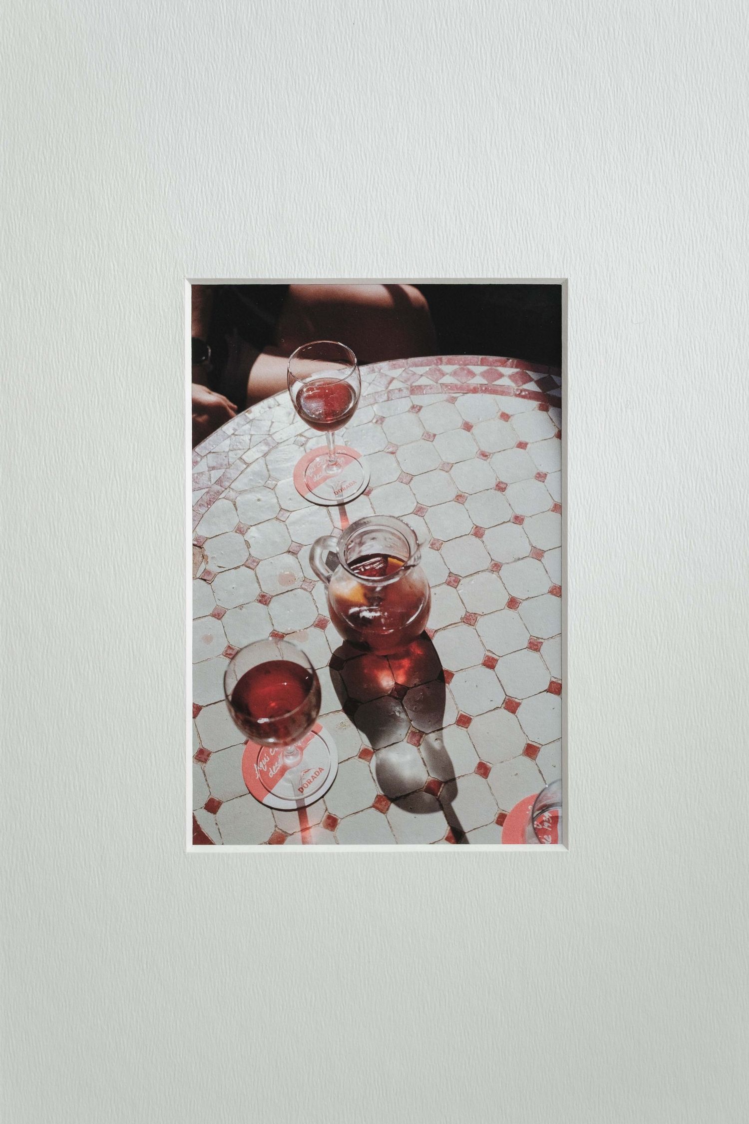 Three wine glasses filled with rose wine sitting on a white tablecloth with pink diamond pattern.