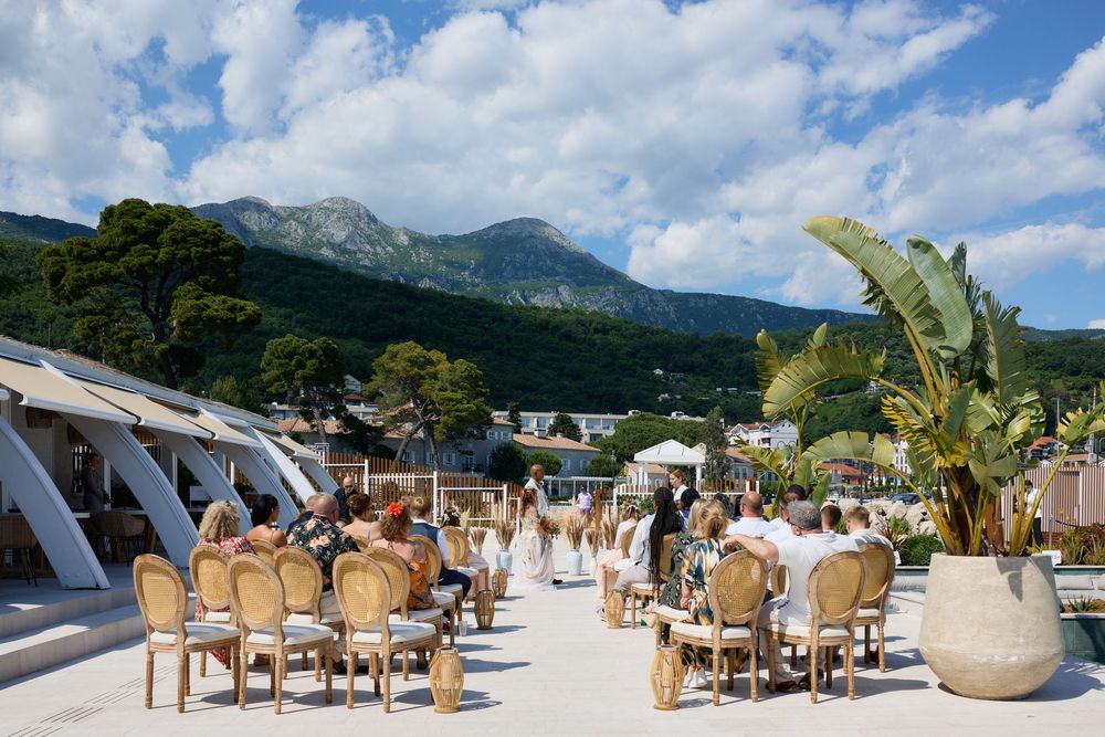 Outdoor wedding reception venue with mountain backdrop and elegant table settings under blue skies.